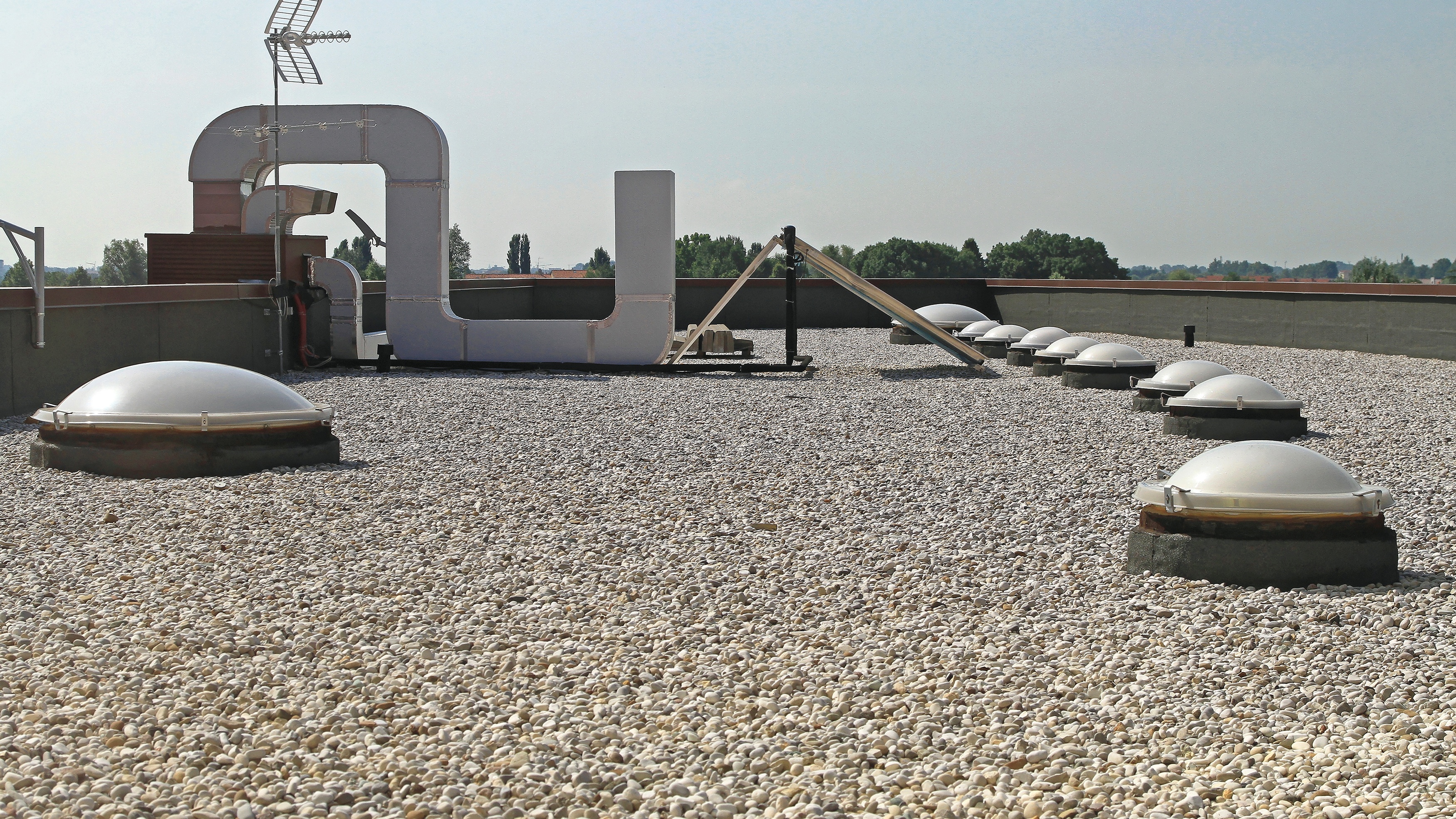 A commercial gravel roof with vents and HVAC ductwork