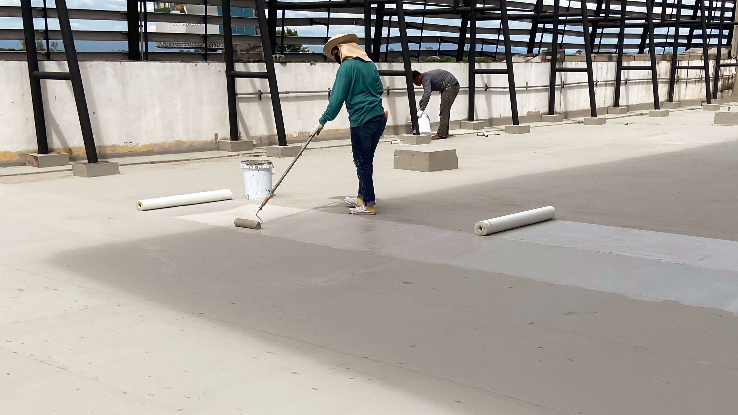 Roof restoration contractors applying a flat roof coating on a commercial roof