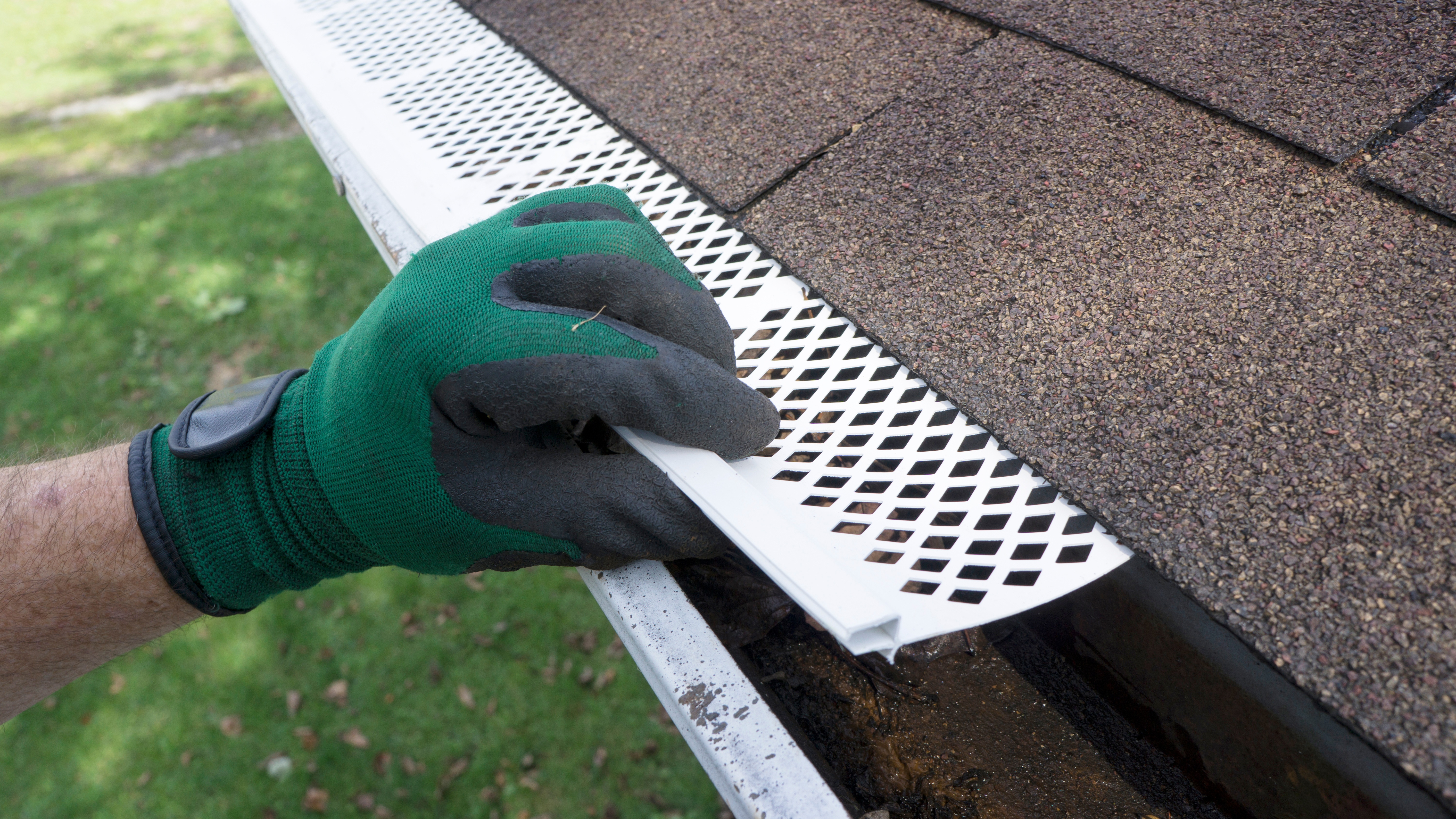 A contractor removing a plastic gutter guard to complete gutter maintenance